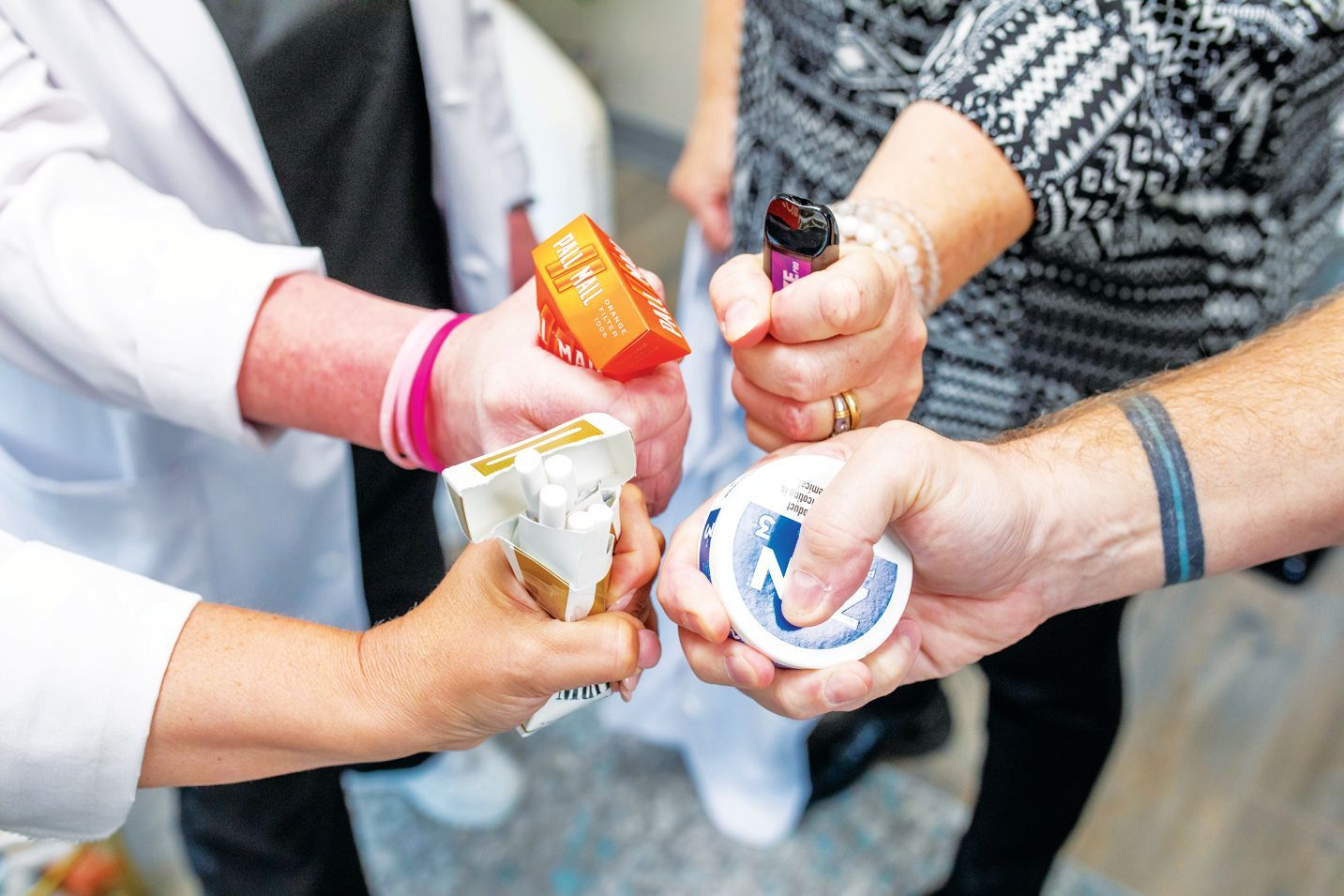 Four hands reach into a center circle, holding various quit-smoking aids, including a vape, patch, and nicotine gum.