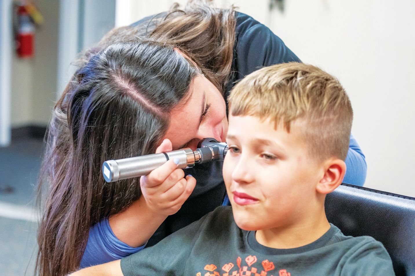 A healthcare provider uses an otoscope to examine a patient’s ear in a clinical setting.