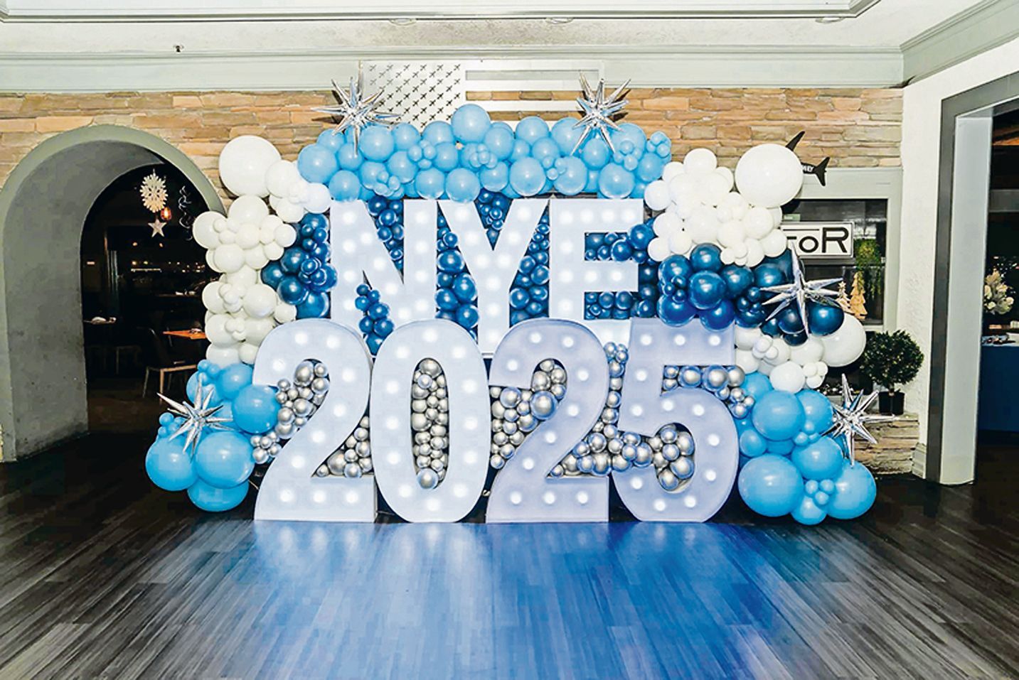 A blue, white, and silver balloon display featuring marquee letters spelling 