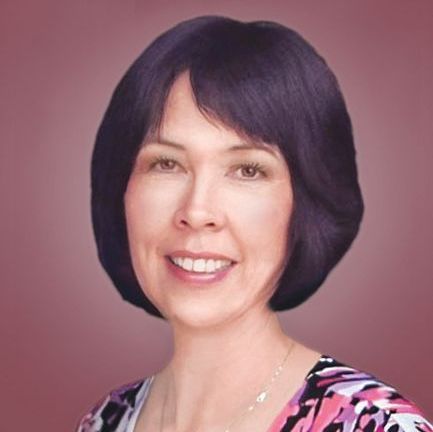 A smiling person with dark hair, wearing a patterned top against a soft, solid mauve background.