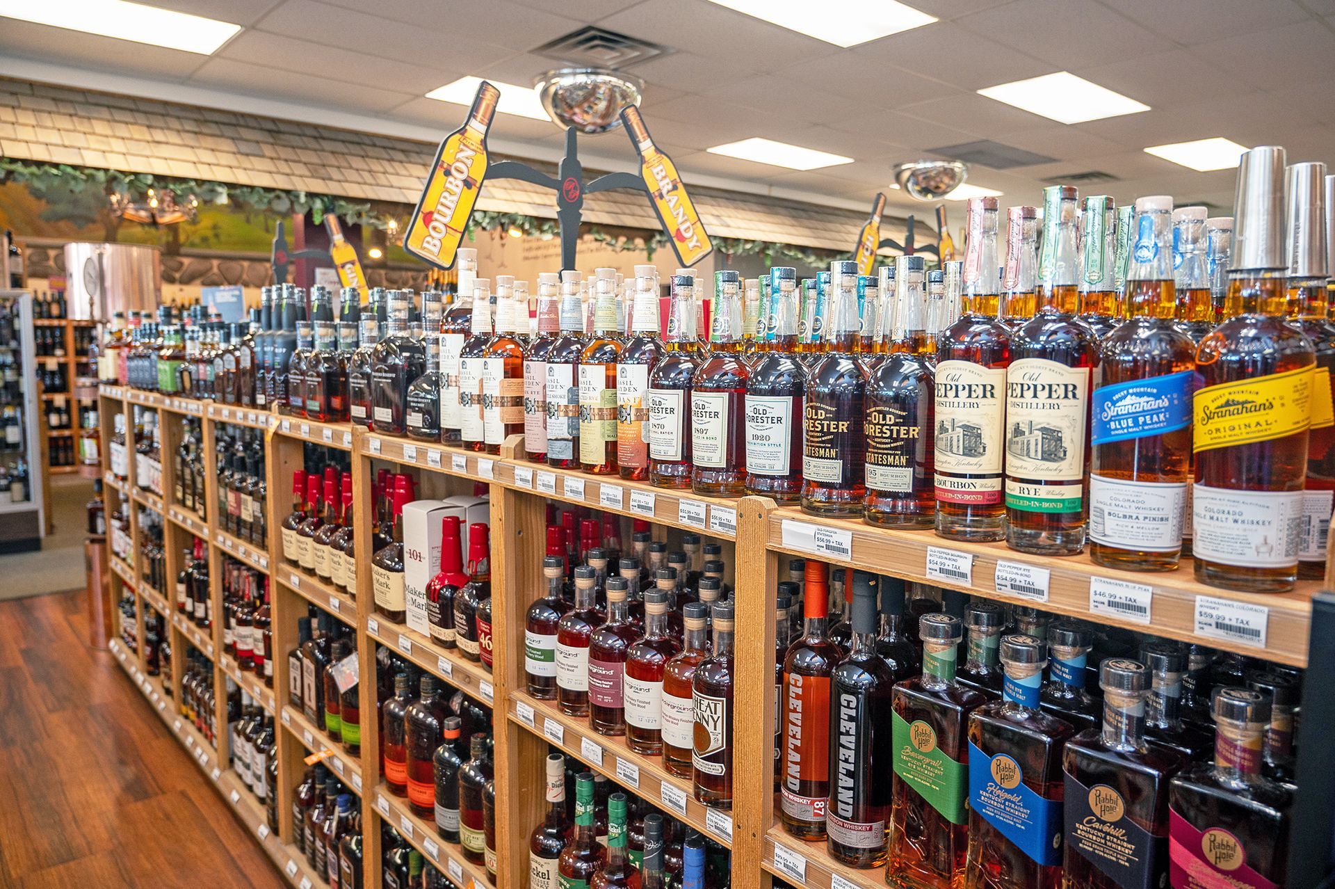 Shelves in a liquor store stocked with various bottles of spirits and whiskey, viewed from a slightly angled perspective.