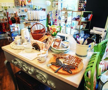 A display table in a gift shop featuring decorative home goods, including kitchenware, a basket, and dragonfly accents.
