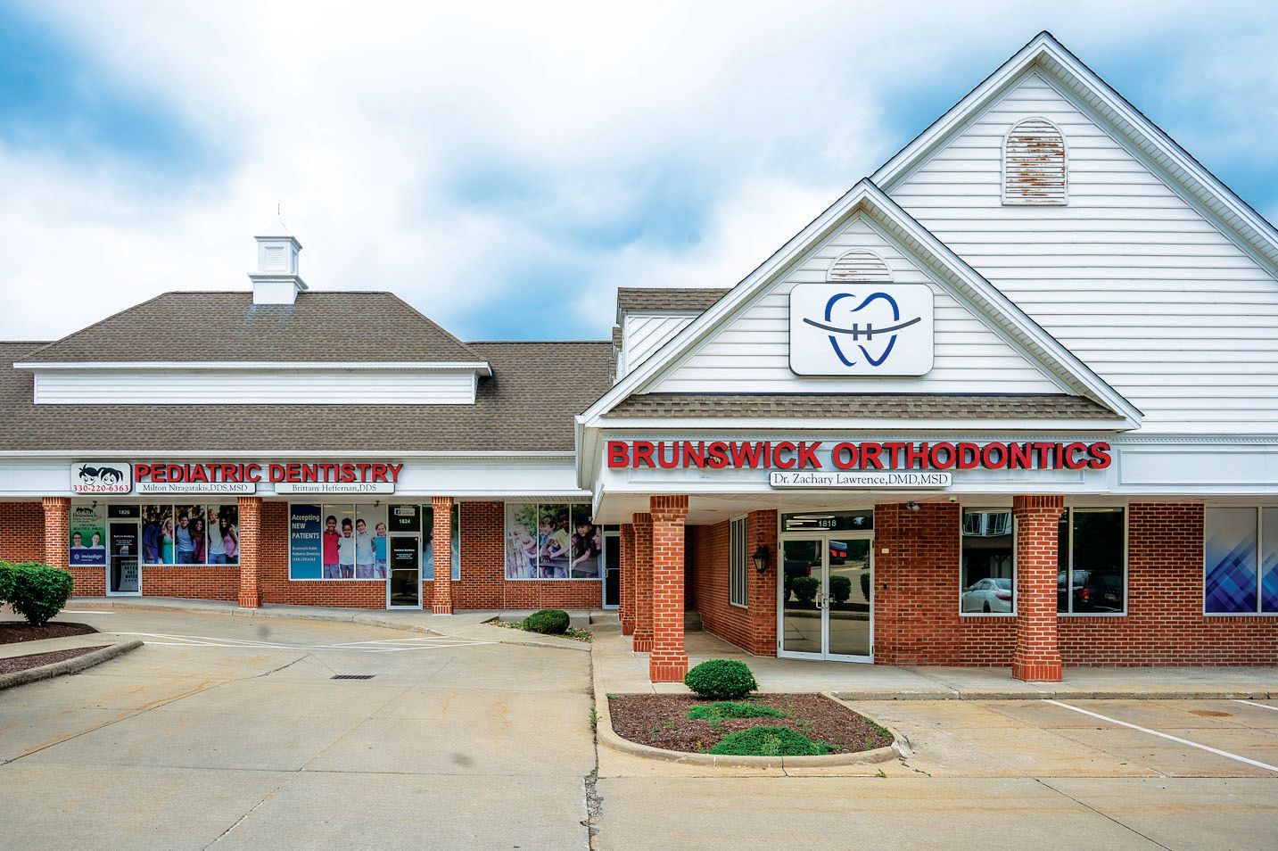 The exterior of a brick building housing a pediatric dentist and Brunswick Orthodontics under a bright, cloudy sky.