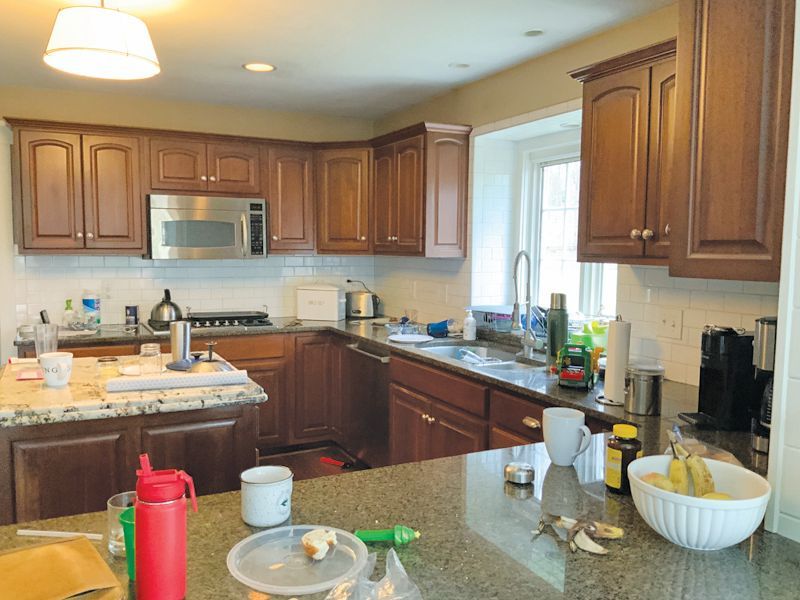 A spacious kitchen with dark wood cabinets, granite countertops, a center island, and a sink beneath a window.