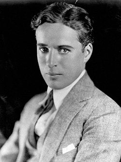 A portrait of Charlie Chaplin, captured in a head-and-shoulders shot wearing a suit jacket with a collared shirt and tie.
