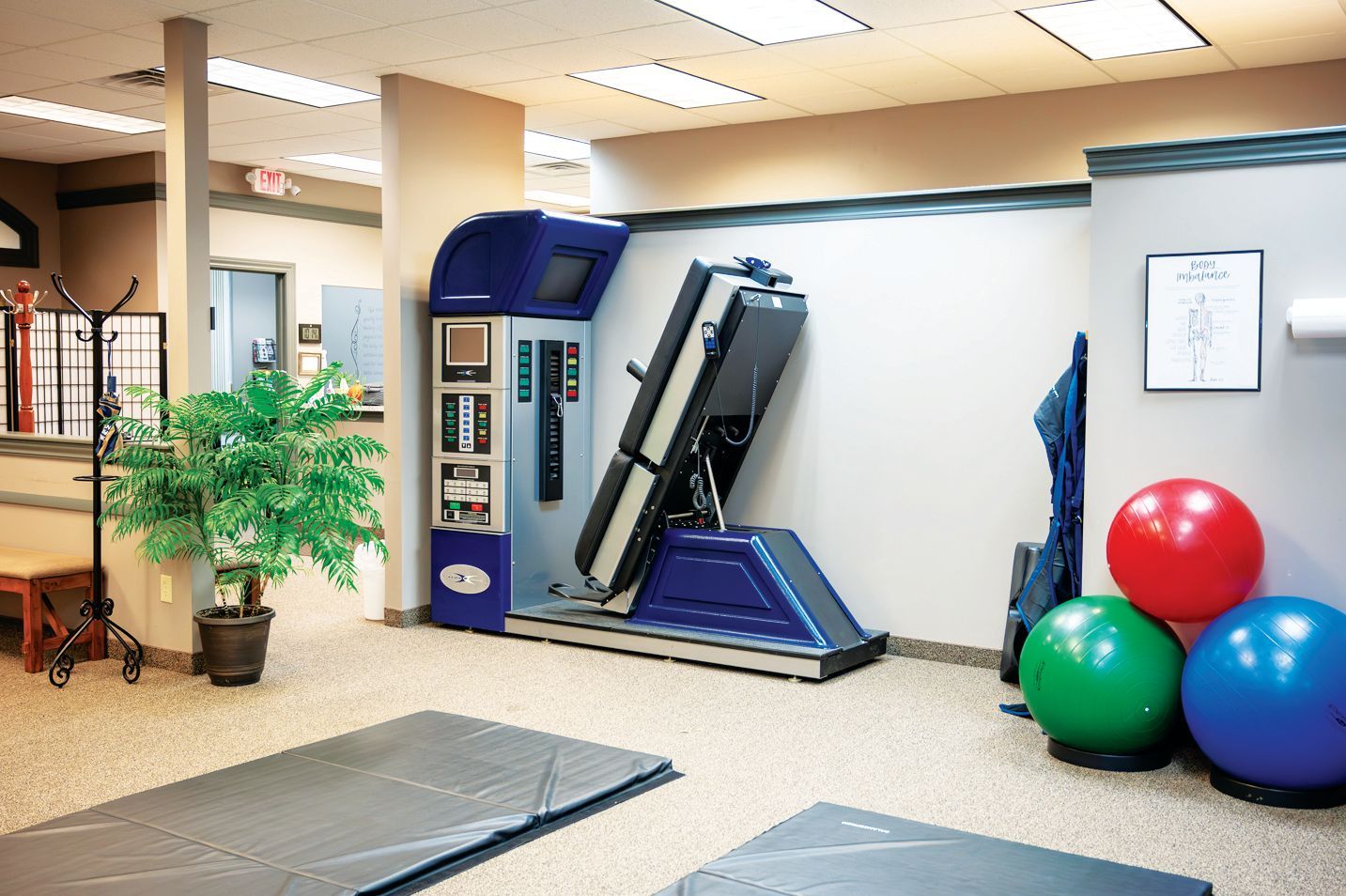 A physical therapy clinic featuring a spinal decompression machine, exercise balls, and floor mats.
