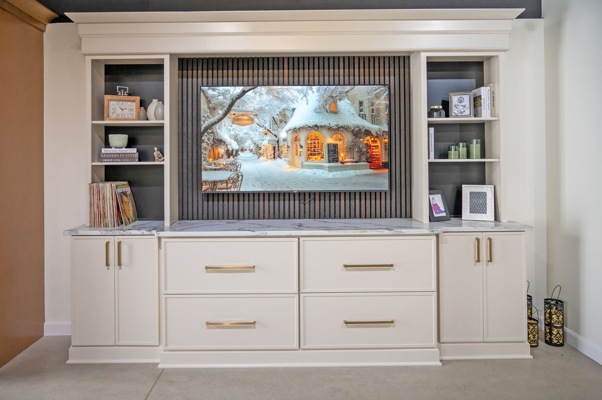 A large cream-colored media unit with built-in shelves, cupboards, and drawers surrounding a television on a slatted wall.