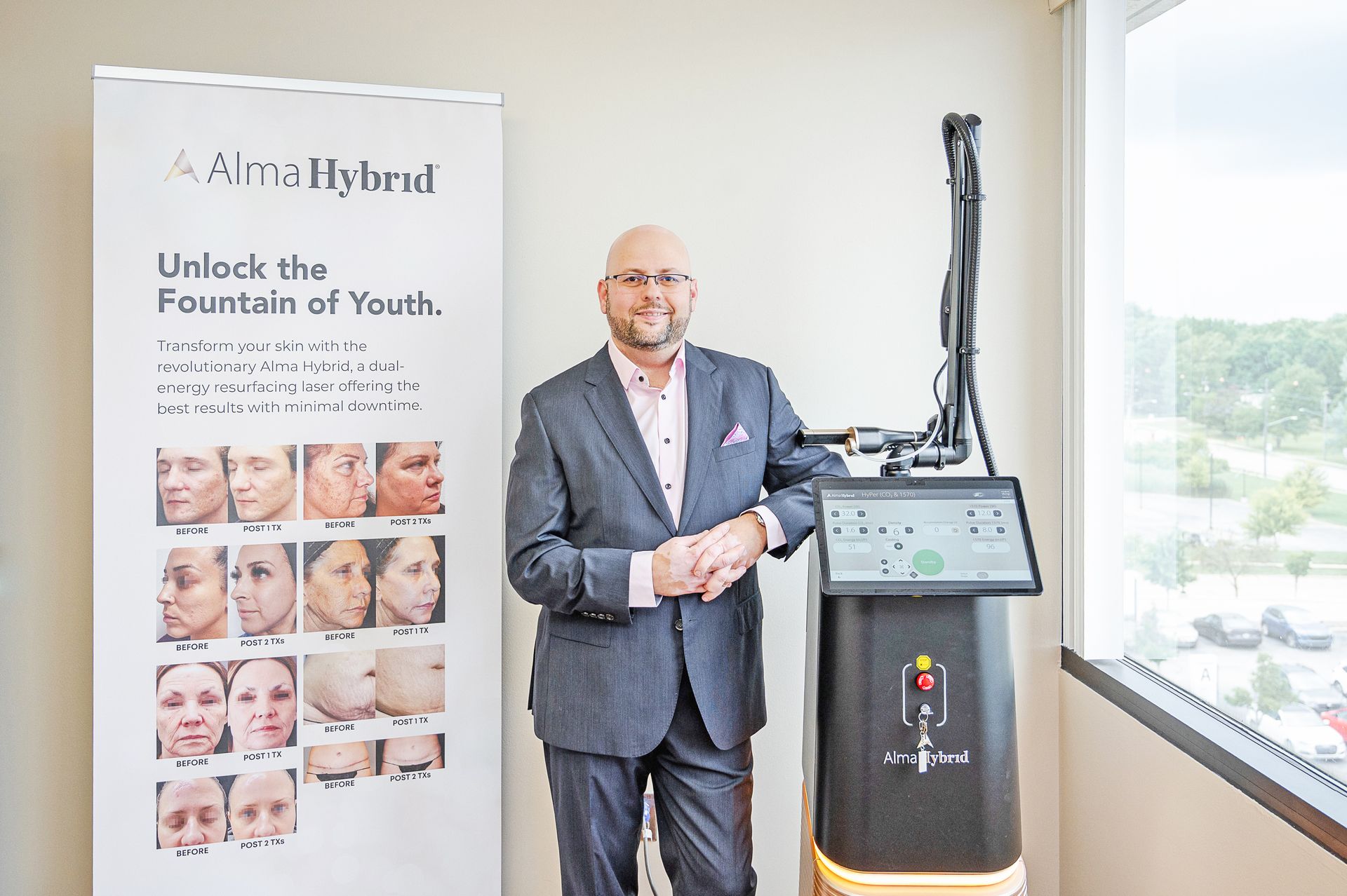 A man in a suit stands next to a Halo medical laser device beside a promotional banner for skin rejuvenation treatments.