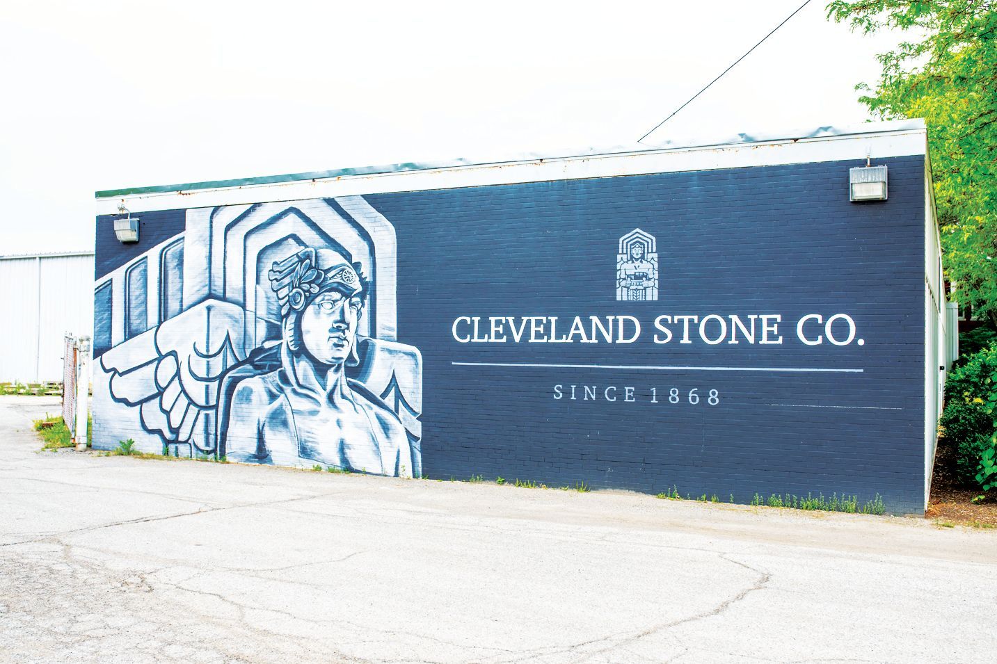 A dark wall mural featuring a stone statue with wings, with 