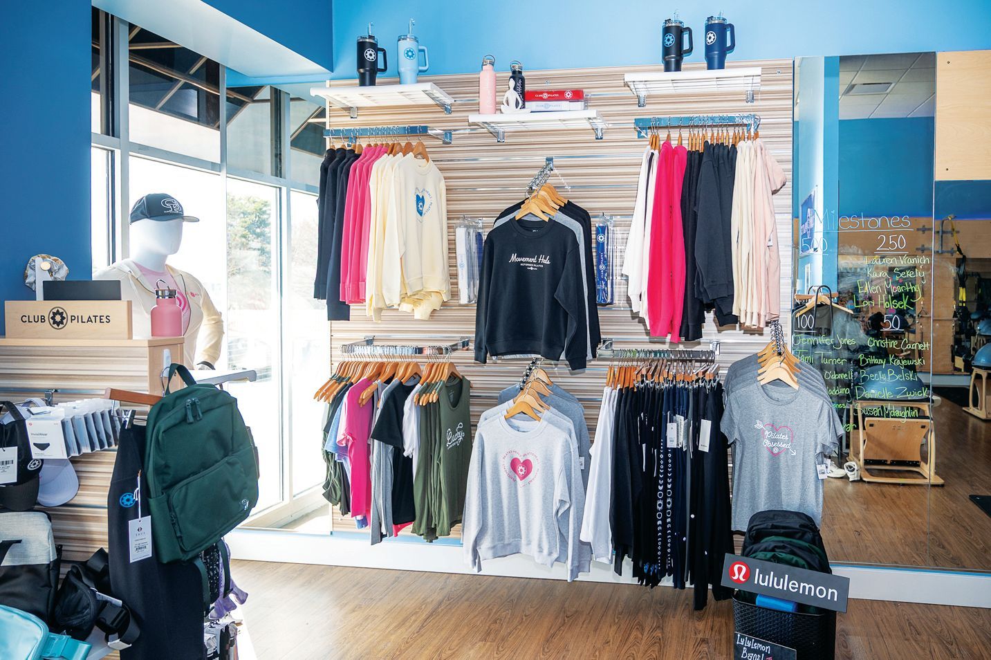 Retail store display featuring racks of hoodies and t-shirts, a mannequin with a cap, and various accessories on shelves.