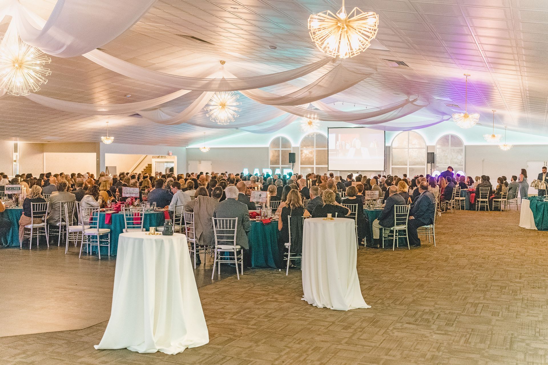 A large, decorated banquet hall filled with guests seated at tables during an indoor event.