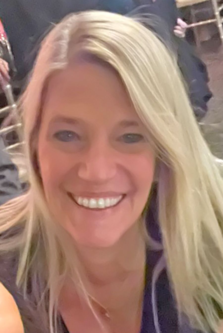 A person with long blonde hair smiling directly at the camera.