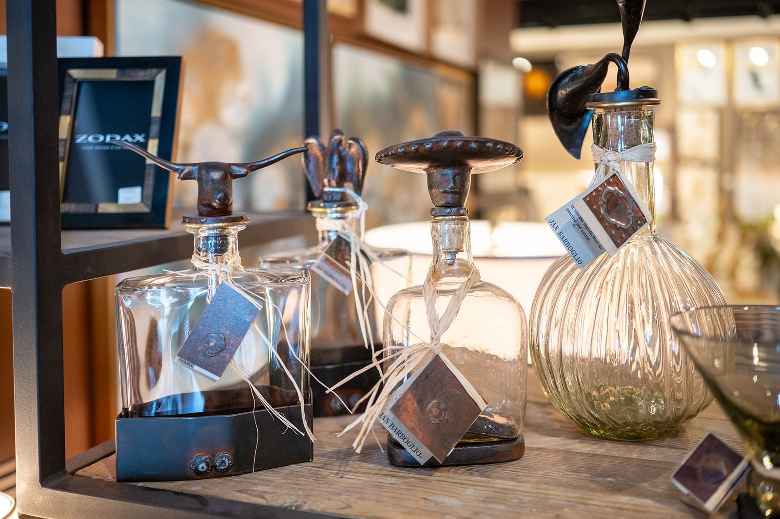Decorative glass bottles with metallic stoppers and price tags displayed on a store shelf.