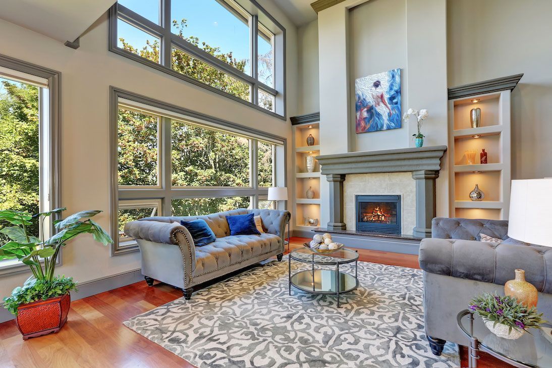 A light-filled living room featuring a fireplace with built-in shelves, a gray sofa, and a patterned area rug.