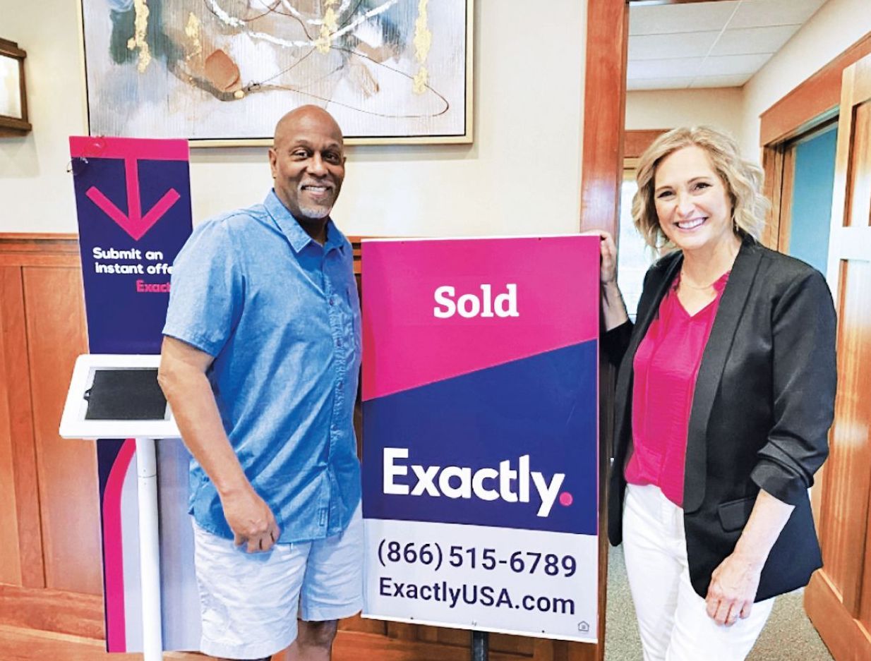 A man and a woman stand smiling beside a 