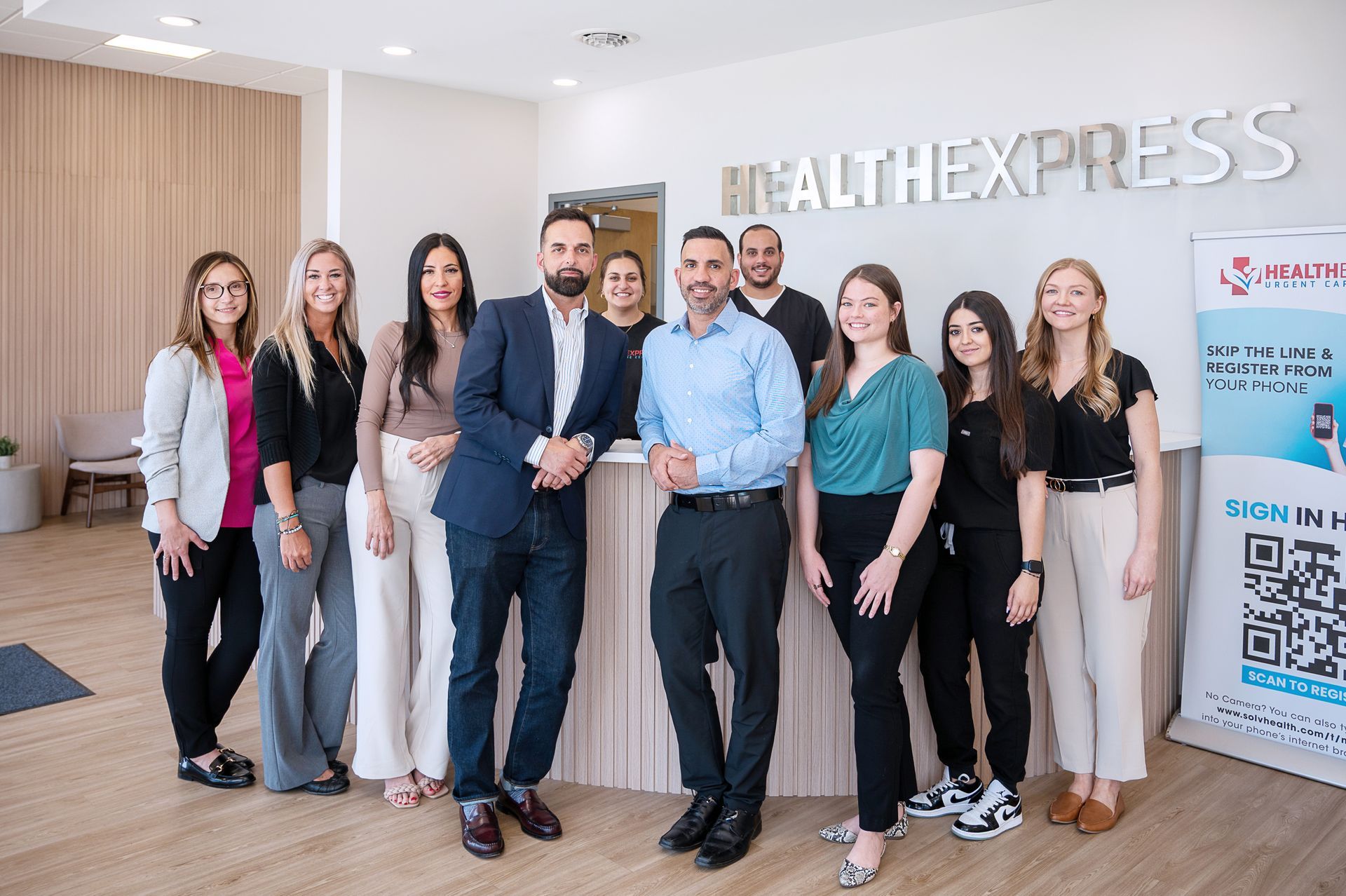 A group of ten professionals in business casual attire standing in the HealthExpress lobby in front of a reception desk.