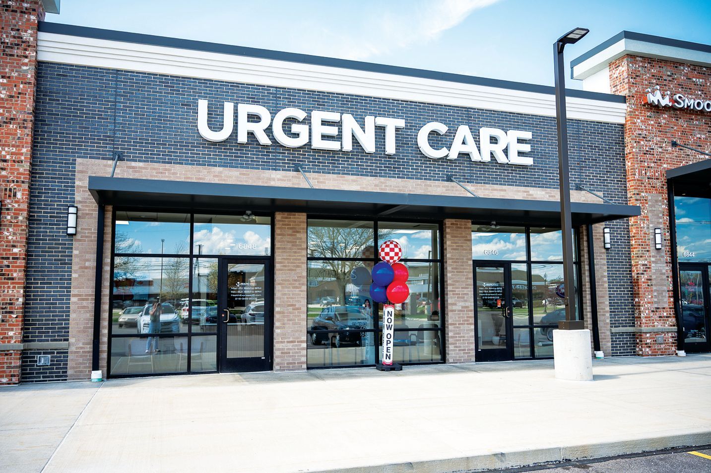 An Urgent Care center storefront with brick exterior, glass doors, and decorative balloons by the entrance.
