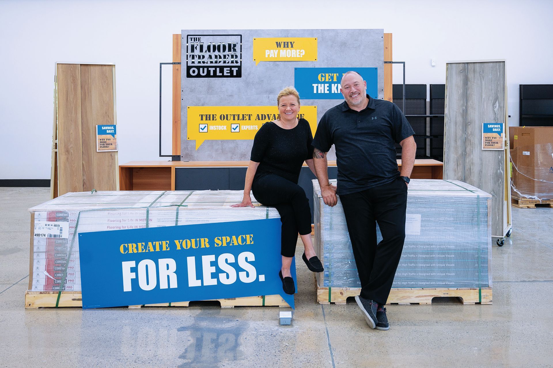 A woman and man stand in a Floor & Decor Outlet store next to palettes of flooring, with a