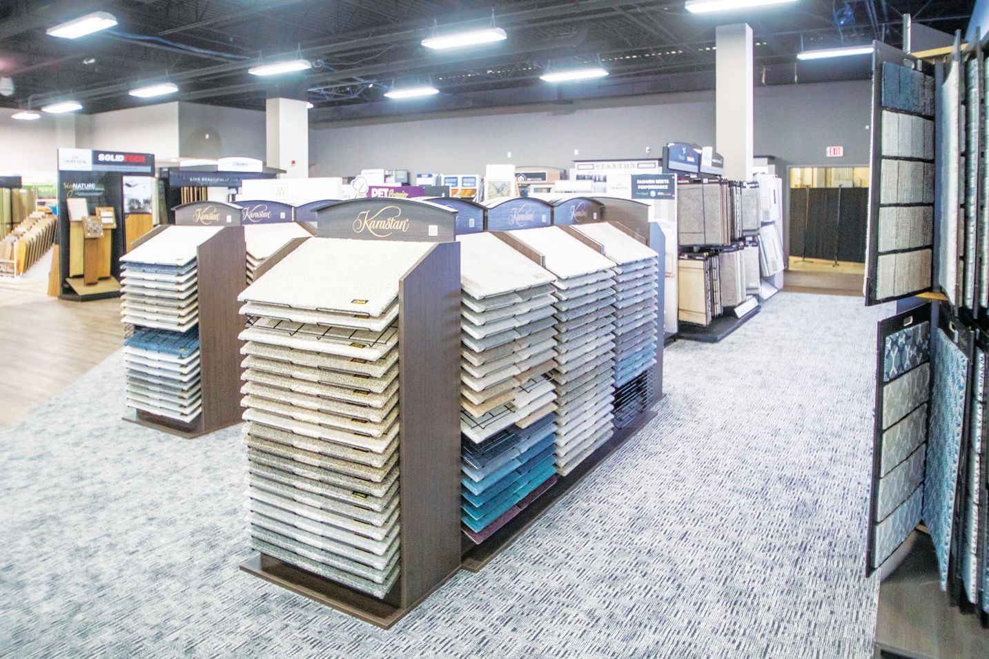 Tile sample display racks organized by color and texture inside a bright, spacious retail showroom.