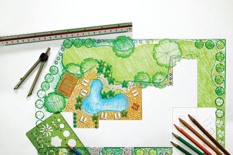 A hand-drawn landscape design plan for a pool area, with a ruler, drafting compass, stencil, and colored pencils.