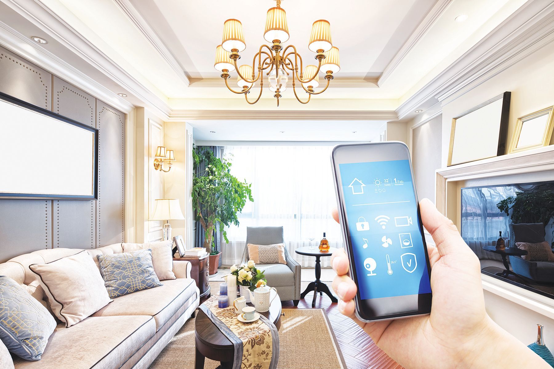 A hand holds a smartphone displaying smart home icons in a bright, modern, elegantly furnished living room.