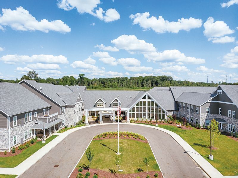 An aerial view of a multi-story stone and grey building with a large semicircular driveway and central flag pole.