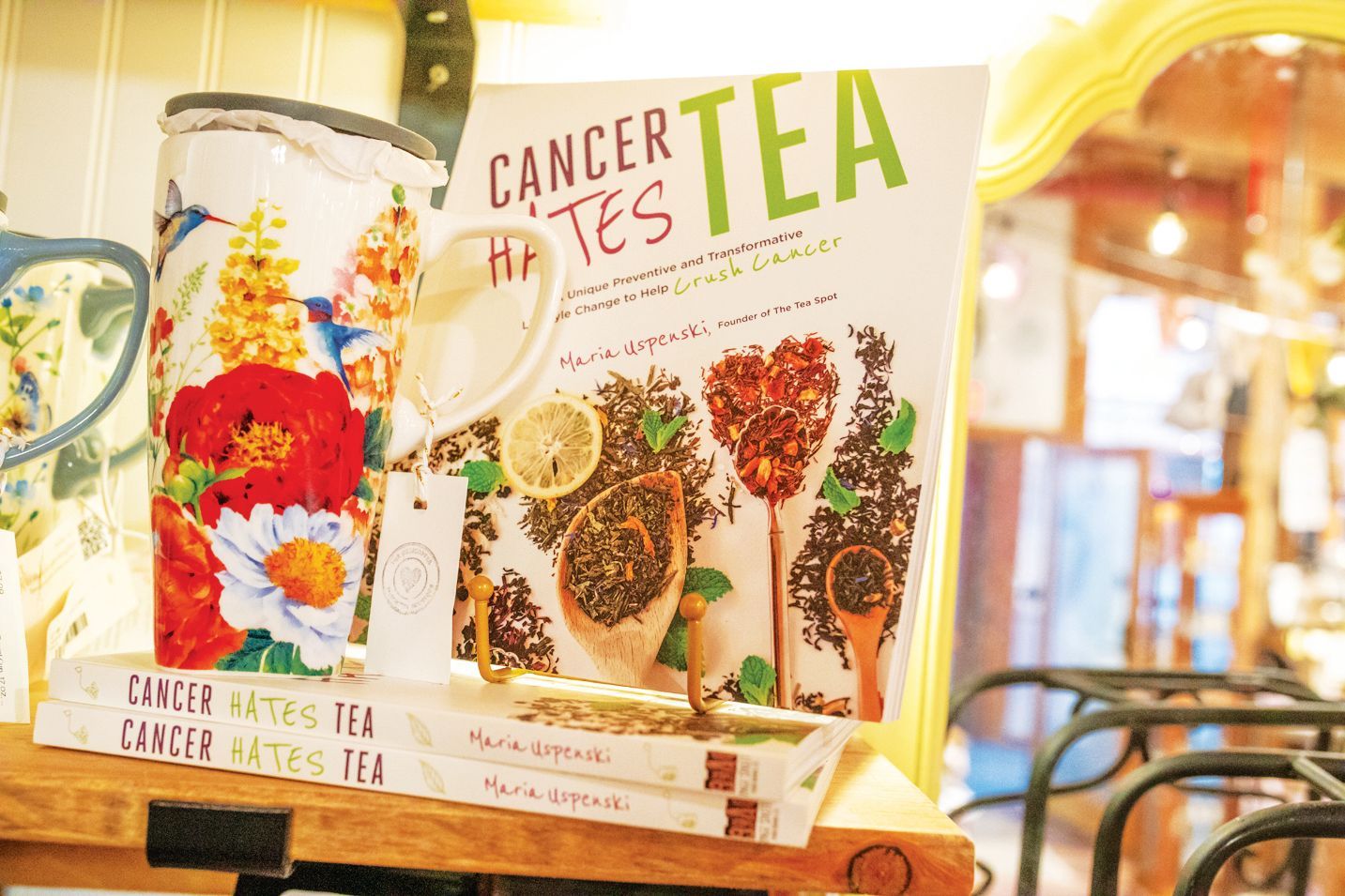 A floral mug stands next to copies of the book 