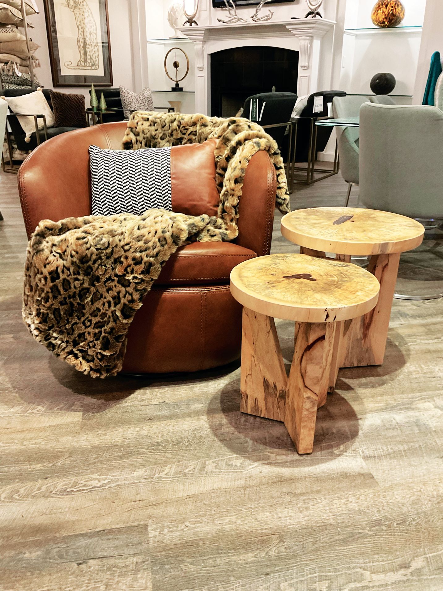A leather armchair with an animal-print throw, featuring two rustic wooden side tables in a modern living room setting.