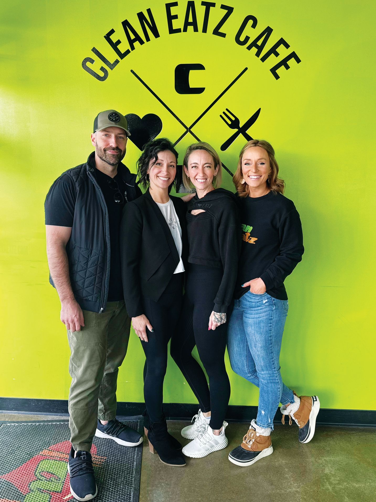Four people stand smiling against a neon green 