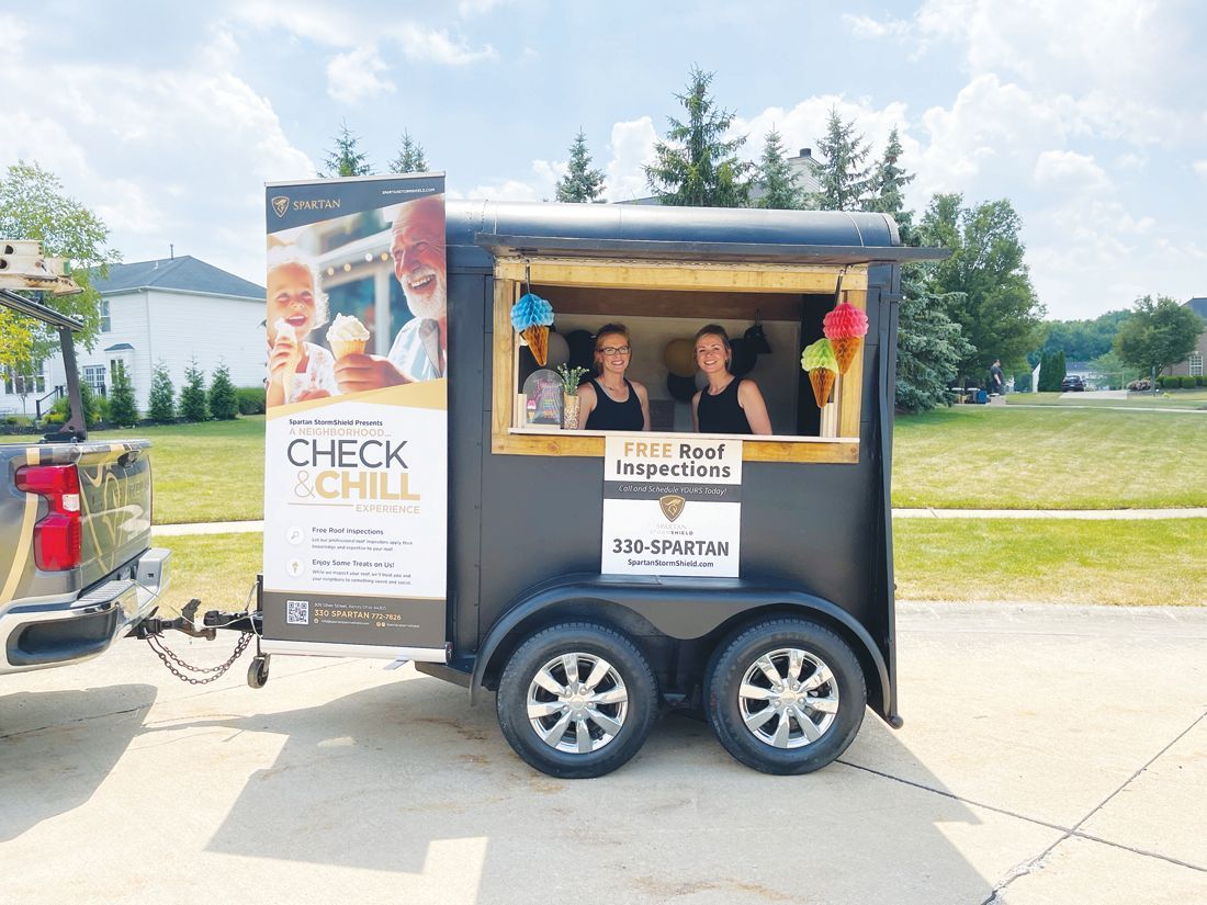 A black food trailer being towed, featuring 
