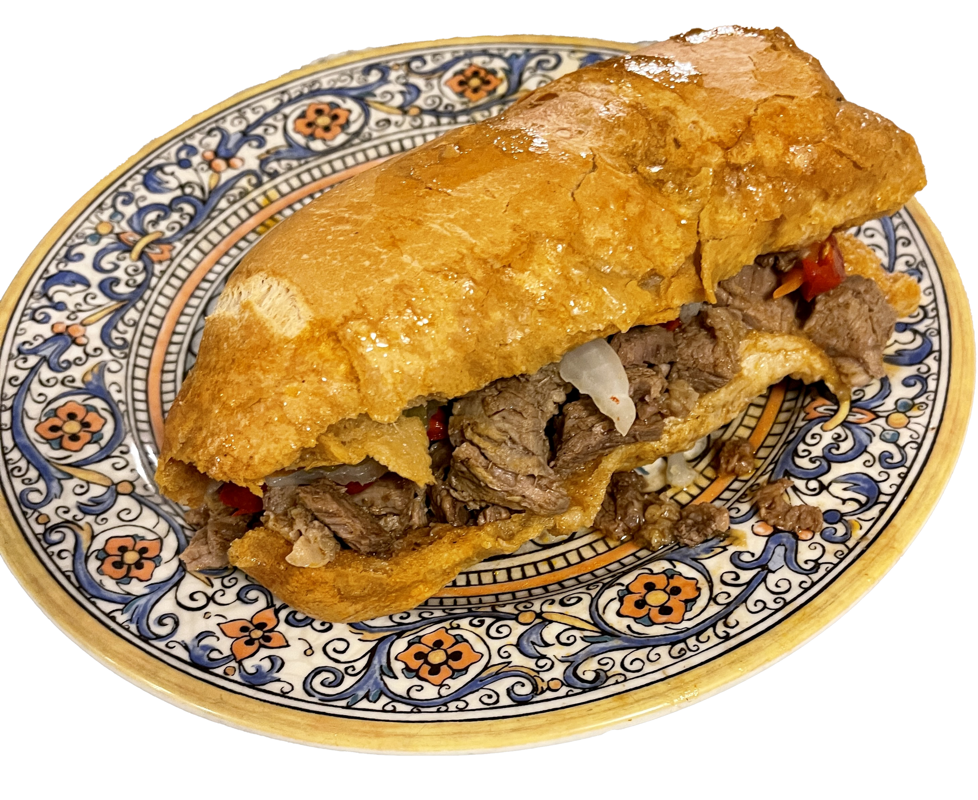 A steak sandwich on a rustic, decorative floral-patterned plate.