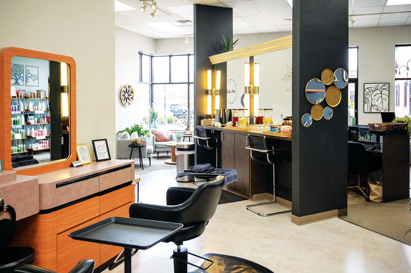A modern hair salon featuring styling stations, black chairs, and a checkout desk in a bright, open space.