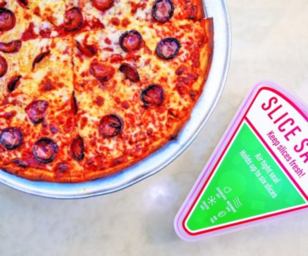 A pepperoni pizza on a metal tray next to a pink-and-green triangular plastic container for storing pizza slices.
