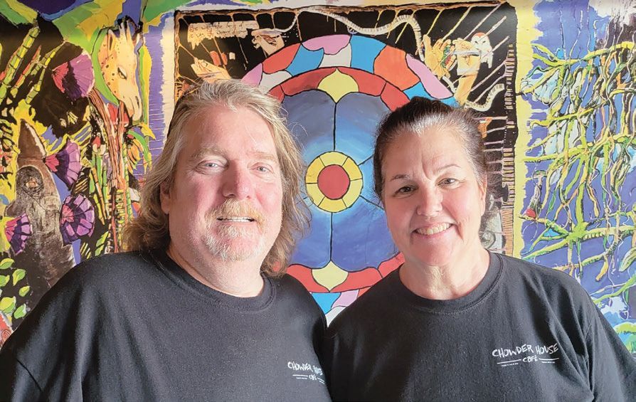 A smiling couple poses in front of a colorful, abstract patterned mural.