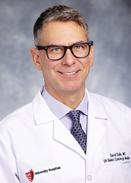 A professional portrait of Dr. David Dole, wearing a white medical coat with a University Hospitals logo and tie.