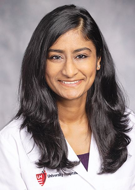 Headshot of a smiling medical professional wearing a white coat with a University Hospitals logo.