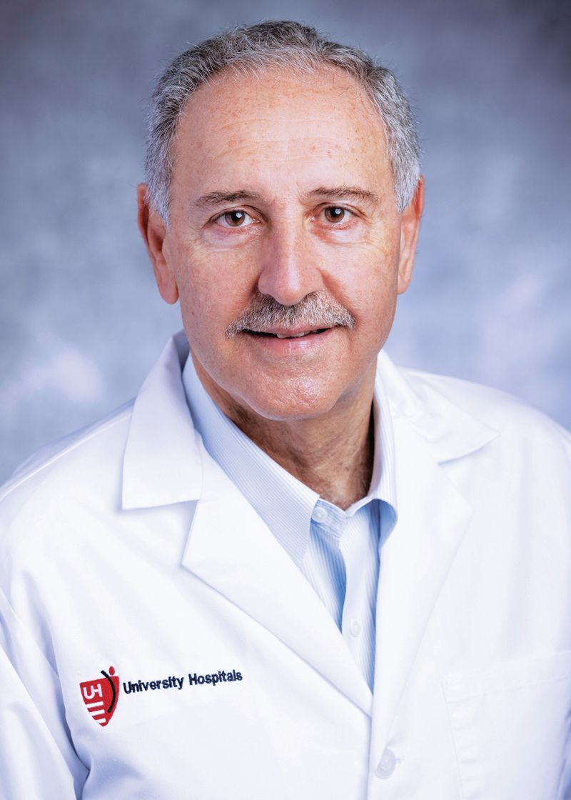 Headshot of a healthcare professional in a white coat with a University Hospitals logo against a blue mottled background.