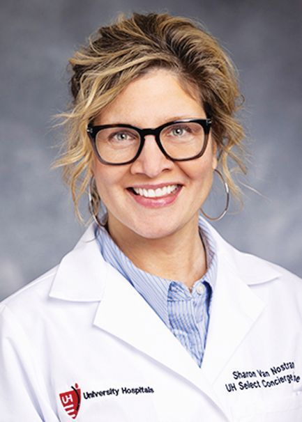 Professional portrait of a physician wearing a white coat with University Hospitals branding and dark-rimmed glasses.