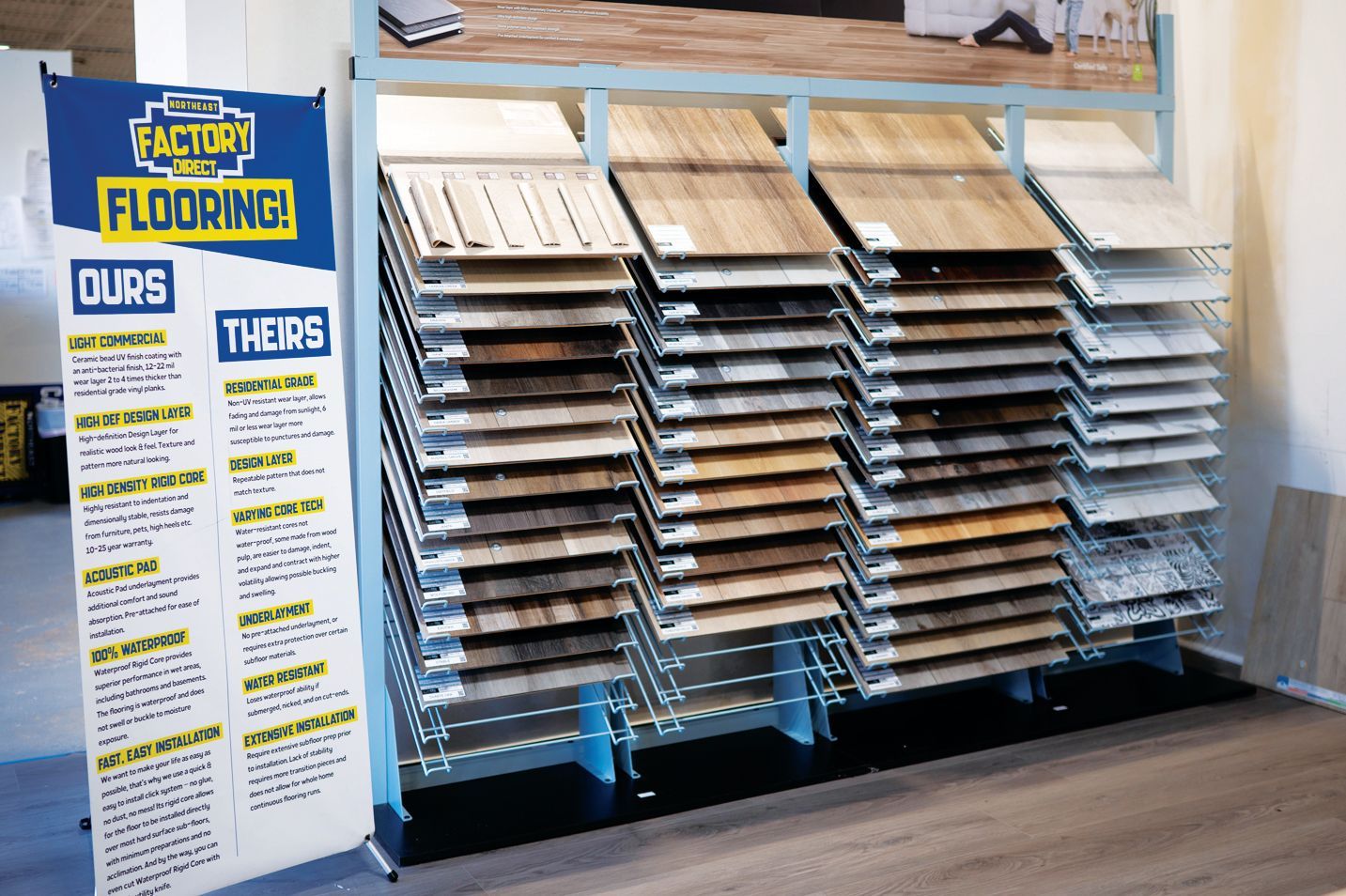A flooring store display rack features rows of wood-look planks next to a sign comparing 