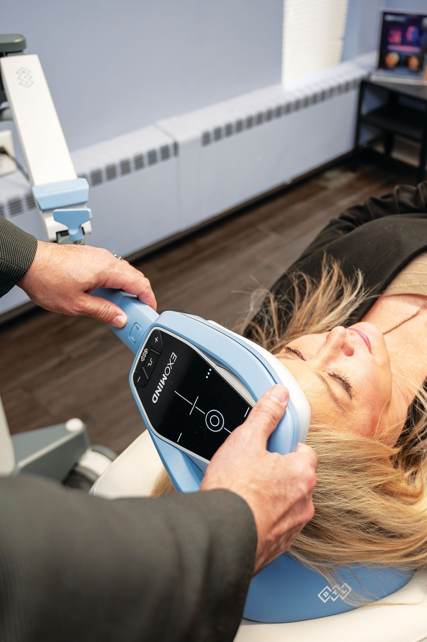 A clinician uses a handheld CoolSculpting device on a patient's face in a clinic setting.