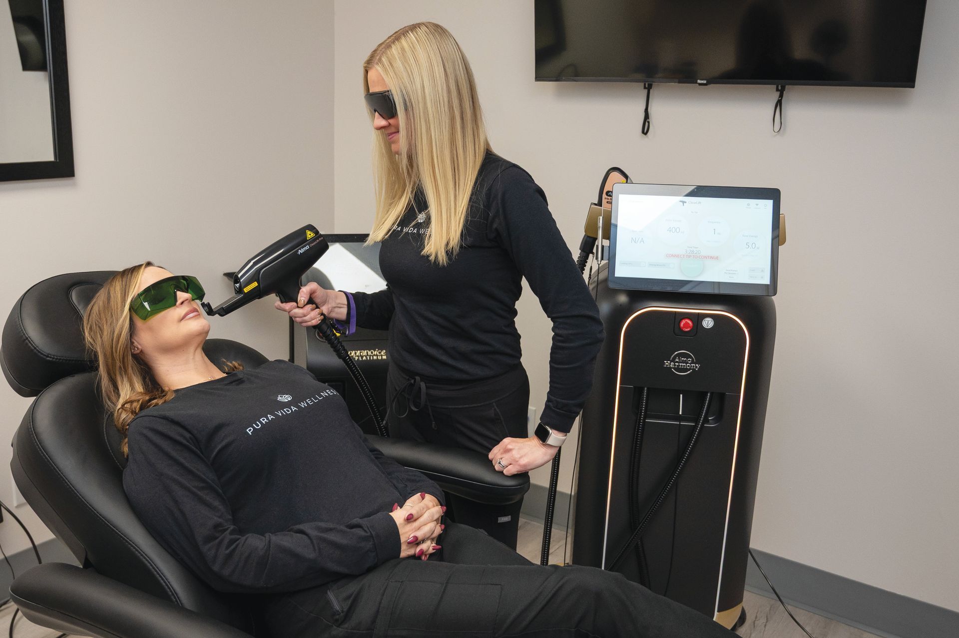 A person in a chair receiving a laser facial treatment from a professional in a clinical office setting.