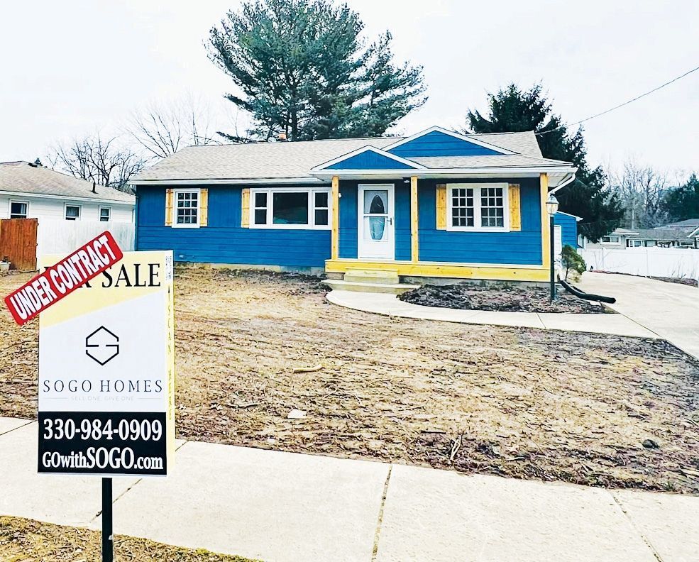 A bright blue house with yellow trim and a white door, with a SOGO Homes 