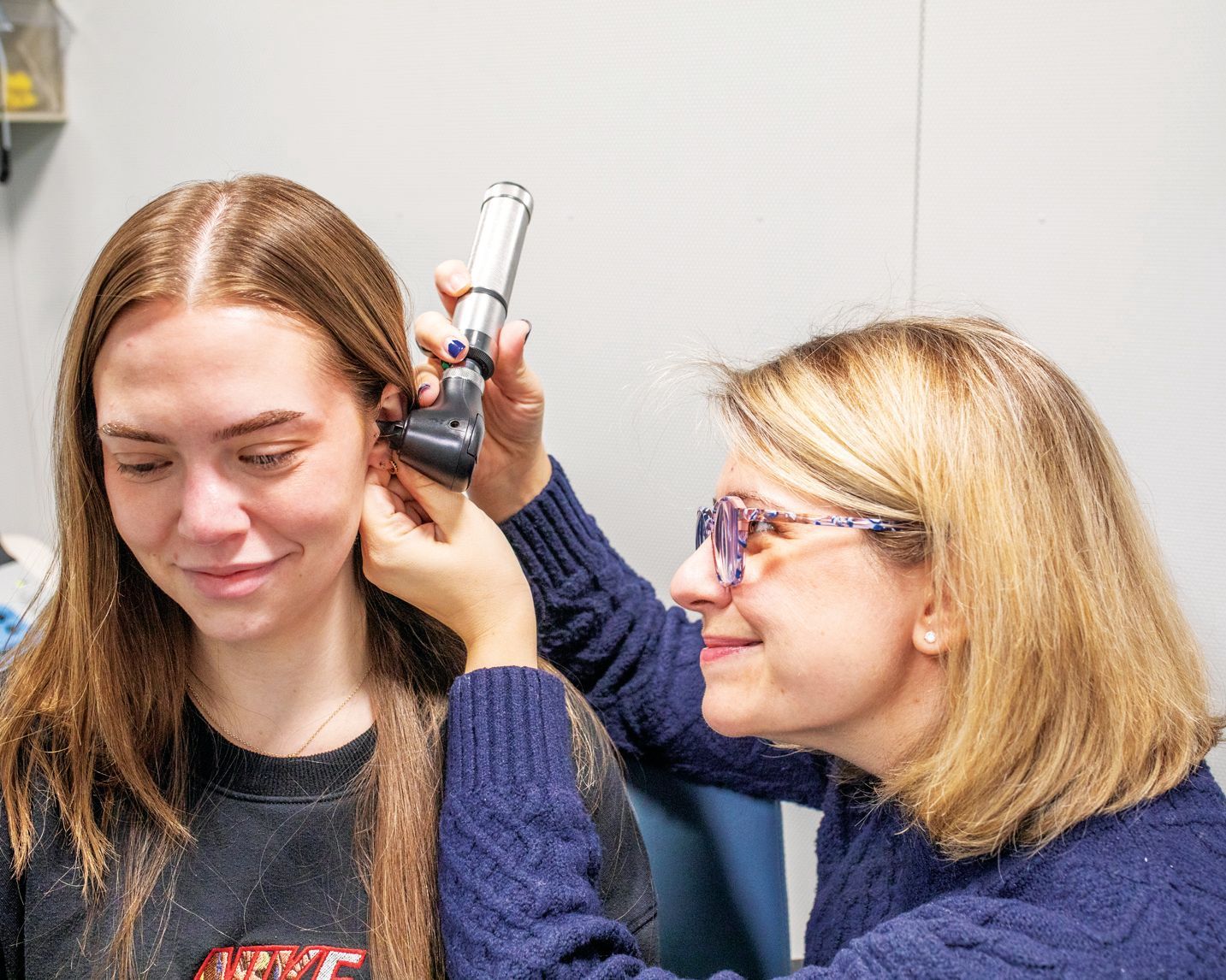 A clinician uses an otoscope to examine a patient’s ear in a medical office setting.
