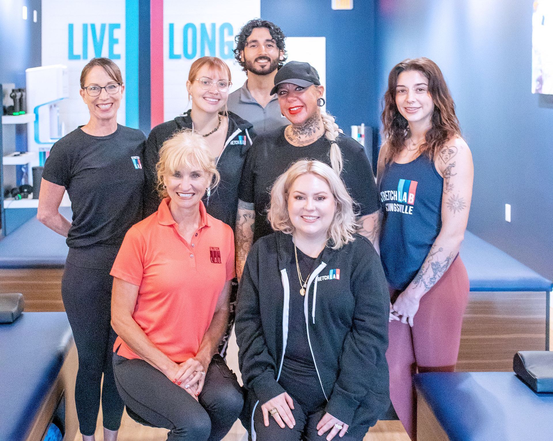 A group of eight people smiling in a gym setting with