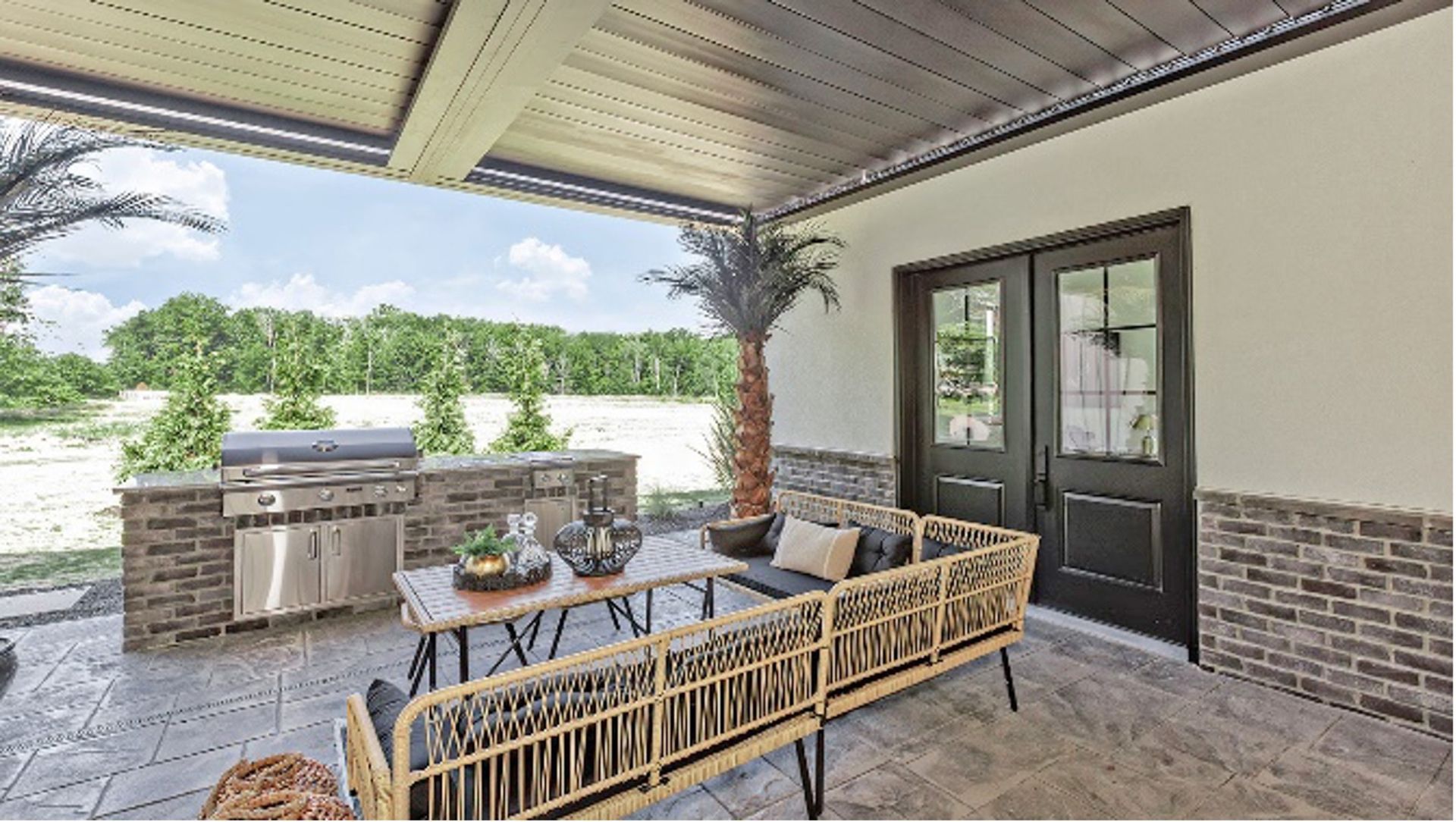A covered outdoor patio with a built-in stainless steel grill, a woven patio set, and glass French doors.