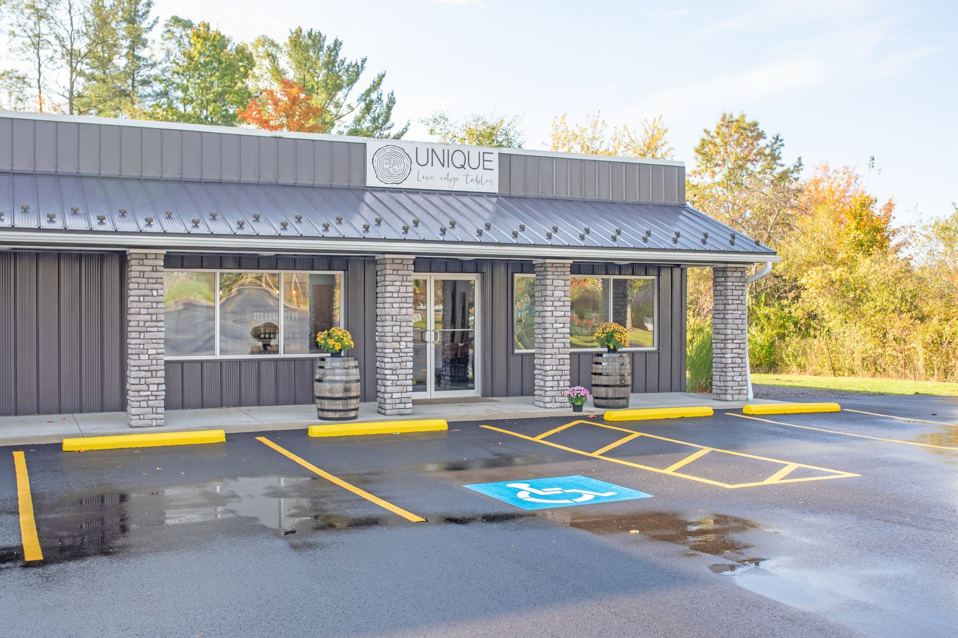 A single-story commercial building with grey siding, stone pillars, and a parking lot with a handicap accessible space.