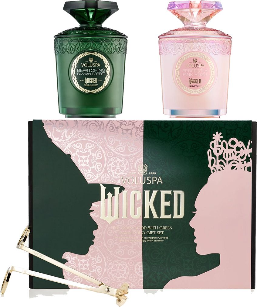 A Voluspa Wicked candle gift set featuring two candles in green and pink, a box with character silhouettes, and a wick trimmer.