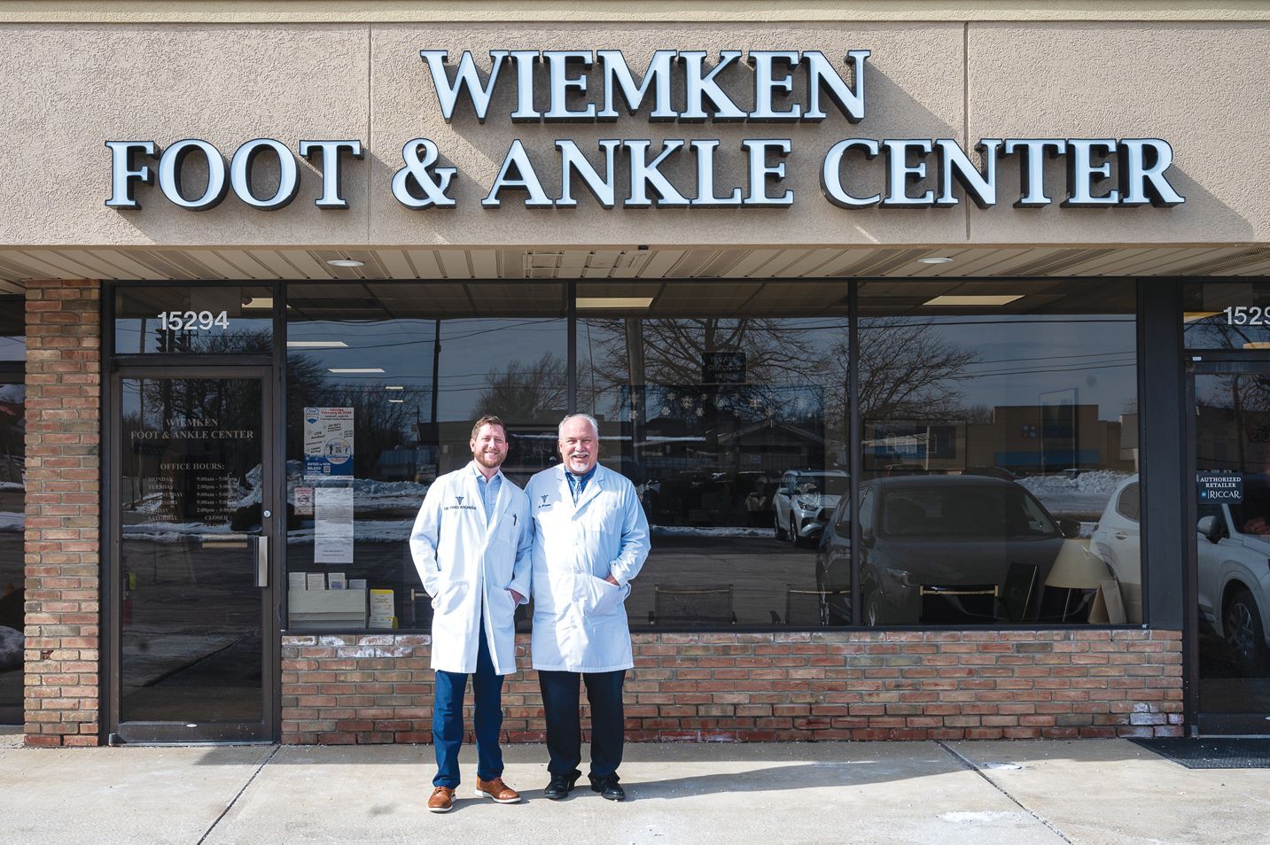 Two medical professionals in white lab coats stand outside the Wiemken Foot & Ankle Center storefront.