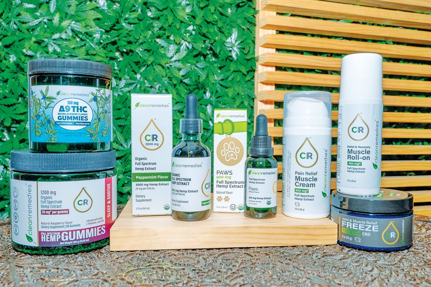 A display of CR branded skincare products and supplements in jars, bottles, and dropper vials on a wooden board.
