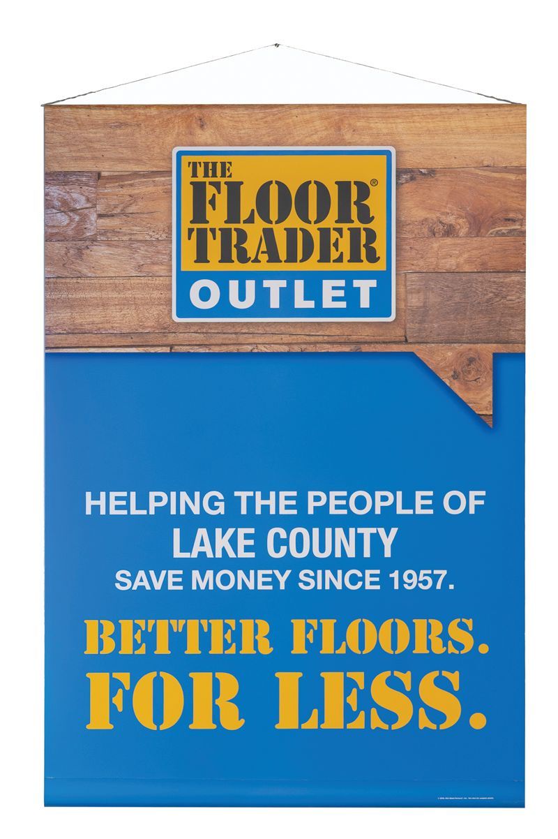A hanging sign for The Floor Trader Outlet, with wood grain background and blue text reading 